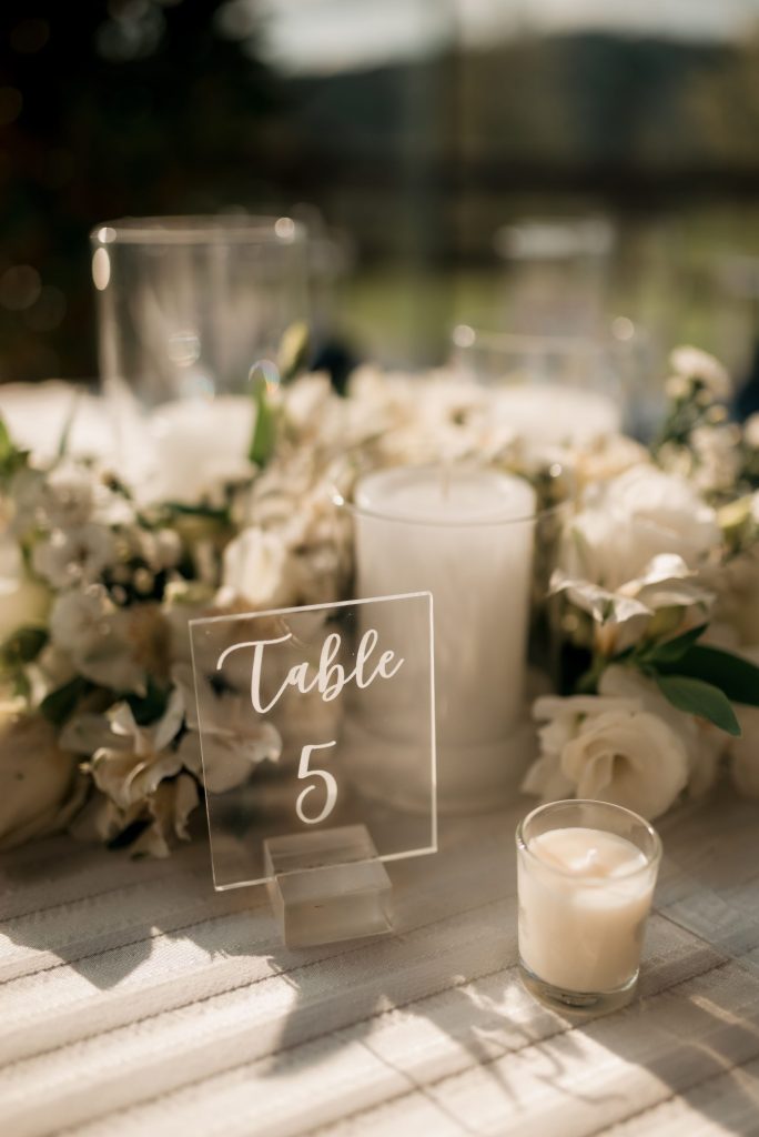 Close-up of a wedding table setup with candles and white flowers around a "Table 5" sign.